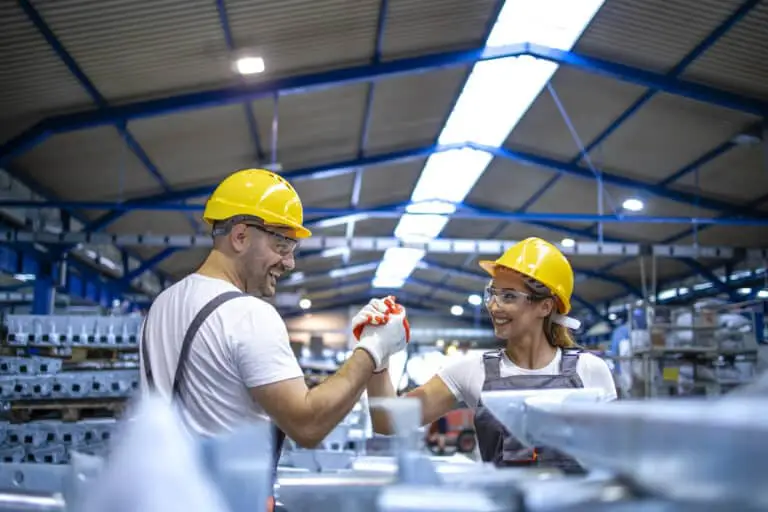 Mitarbeitende an einer Produktionslinie begrüßen sich