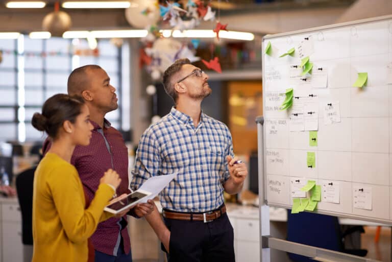 Team arbeitet mit Haftnotizen an einem Whiteboard an einer gemeinsamen Vorgehensweise